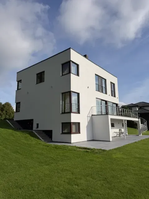 Valge kaasaegne eramu nurkvaates suure rohelise aiaga