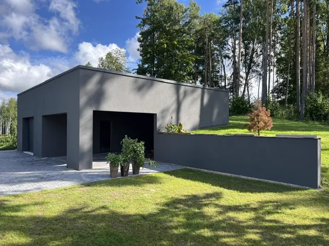 Tumehalli fassaadiga eramu ja tugimüür aias